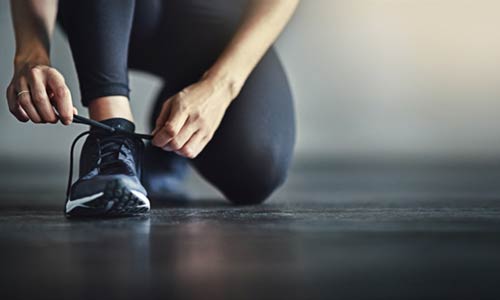 Fitnesskurse im Gesundheitszentrum Northeim - Frau schnürt sich den Schuh im knieen